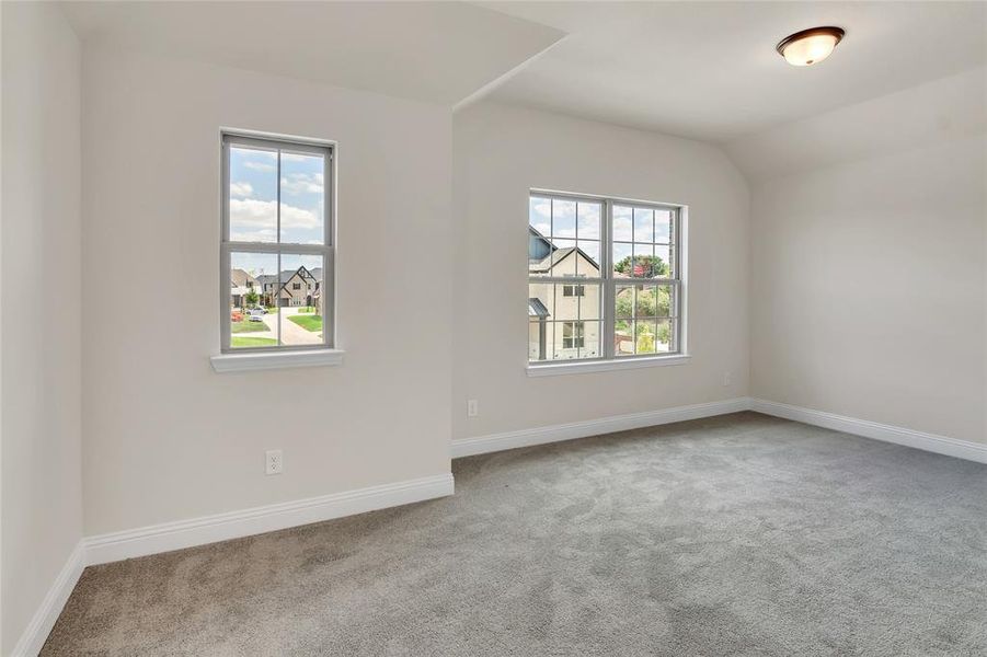 Empty room with light carpet and vaulted ceiling