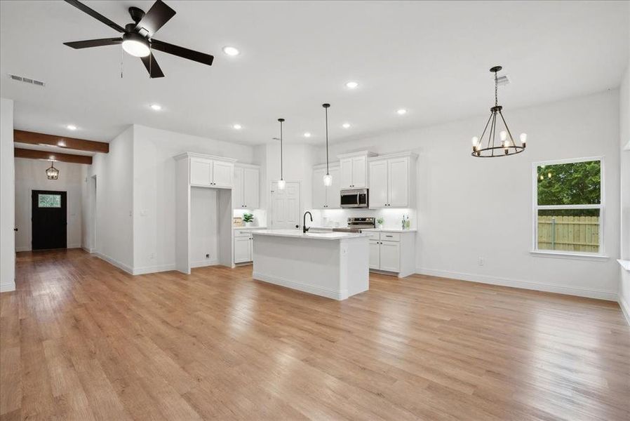 Kitchen with ceiling fan with notable chandelier, light wood-type flooring, decorative light fixtures, and stainless steel appliances