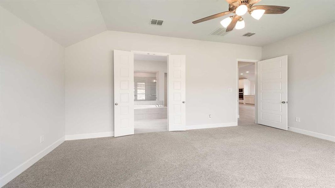 Unfurnished bedroom featuring lofted ceiling, ceiling fan, carpet floors, and ensuite bathroom