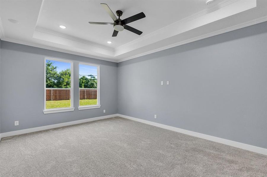 Unfurnished room featuring ceiling fan, a tray ceiling, crown molding, and carpet flooring