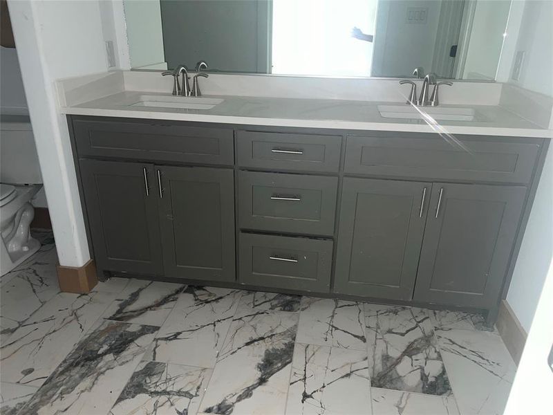 Bathroom featuring double vanity, tile patterned flooring, and toilet