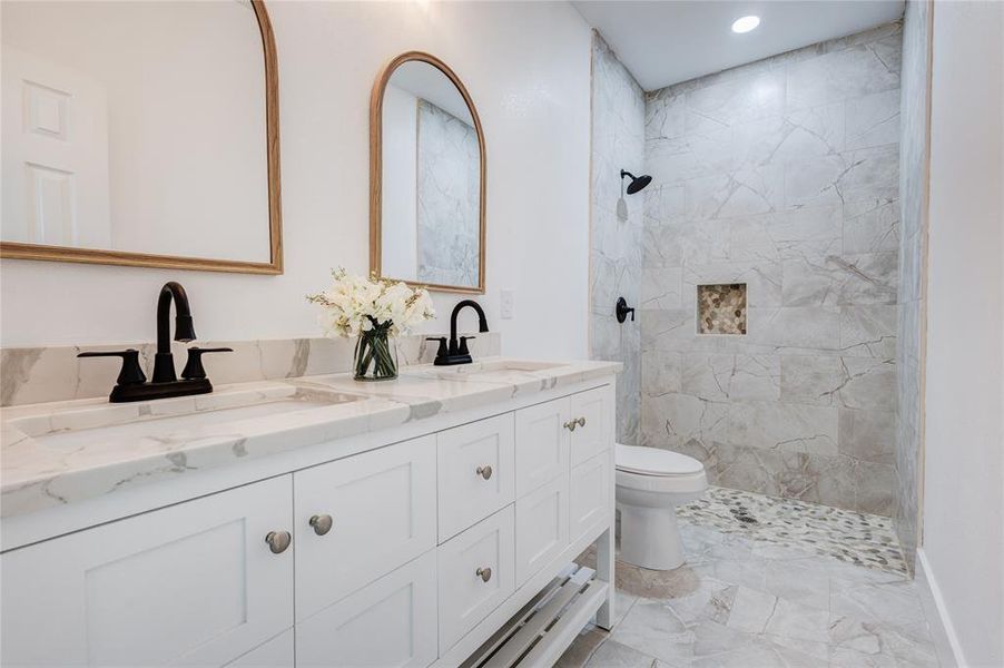 Bathroom featuring vanity, toilet, and tiled shower