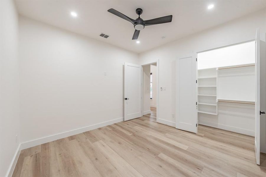 Bedroom featuring ceiling fan, a closet, and blonde plank, wood-like luxury vinyl floors.