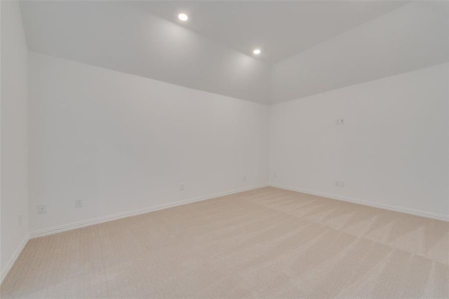 Empty room featuring vaulted ceiling and light colored carpet