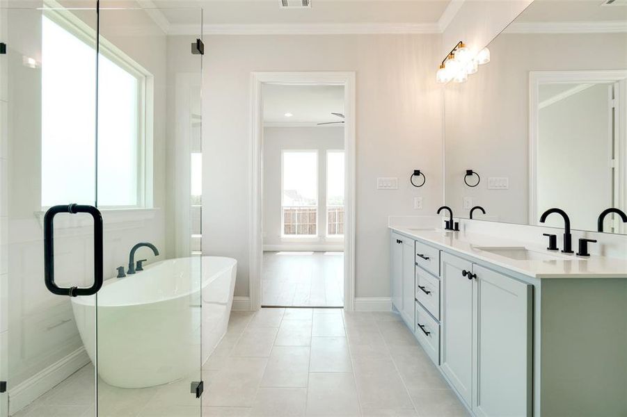Bathroom featuring double sink vanity, ceiling fan, ornamental molding, a tub to relax in, and tile patterned flooring