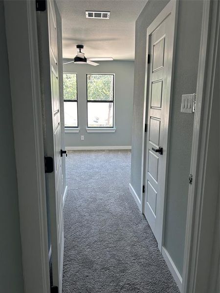 Hallway featuring a textured ceiling and carpet floors