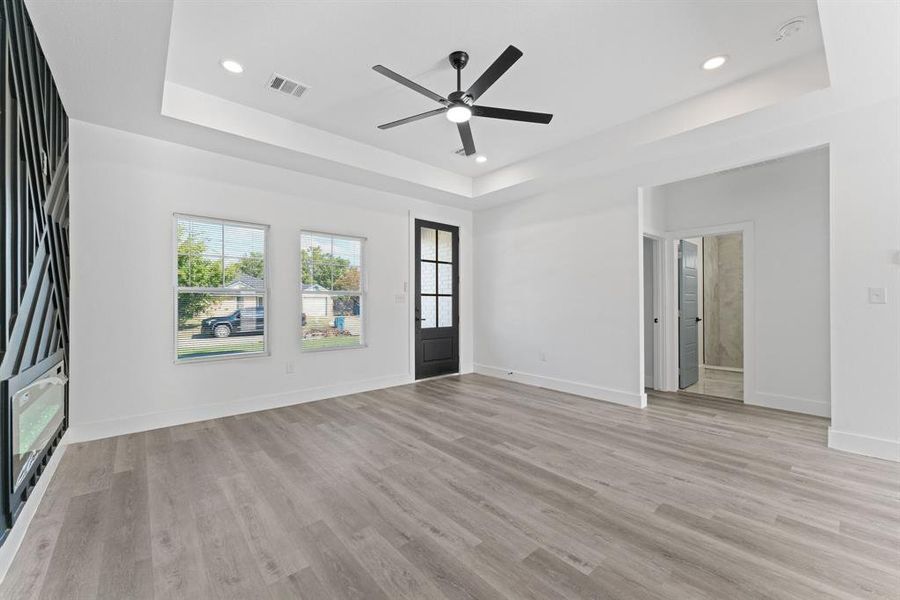 Unfurnished living room featuring ceiling fan, light hardwood / wood-style flooring, and a raised ceiling