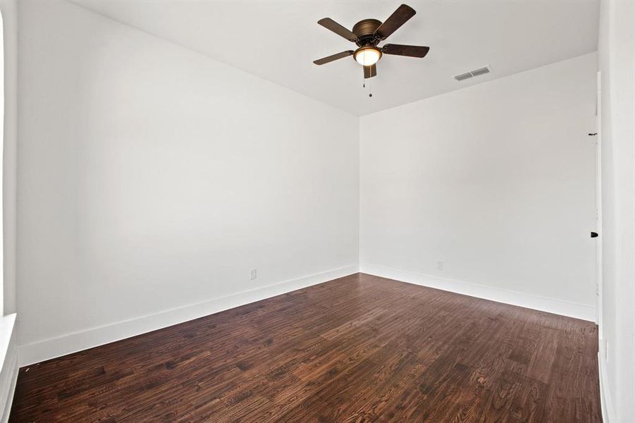 Spare room featuring ceiling fan and dark wood-type flooring