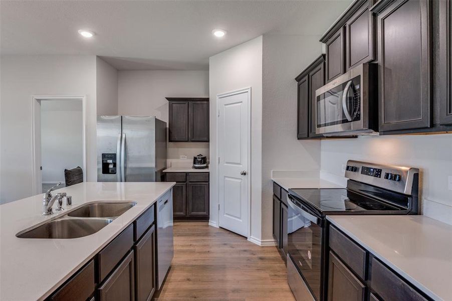 Kitchen featuring sink, dark brown cabinets, stainless steel appliances, and light hardwood / wood-style floors