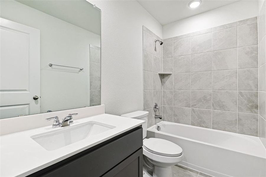 Full bathroom with toilet, tiled shower / bath, vanity, and tile patterned floors