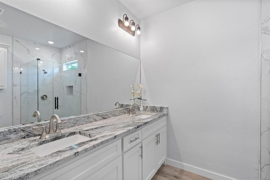 Bathroom featuring vanity, wood-type flooring, and a shower with shower door