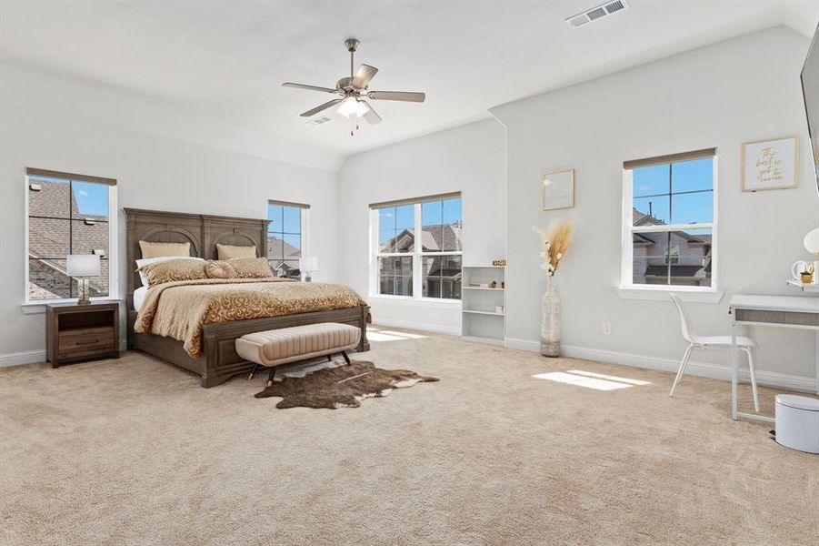 Bedroom featuring ceiling fan, multiple windows, carpet floors, and vaulted ceiling
