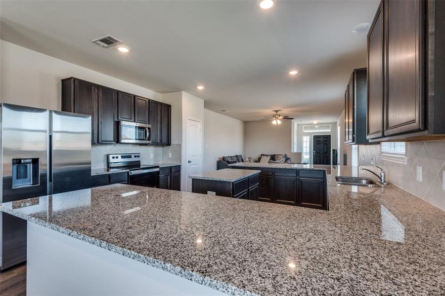 Kitchen featuring sink, kitchen peninsula, a kitchen island, appliances with stainless steel finishes, and light stone countertops