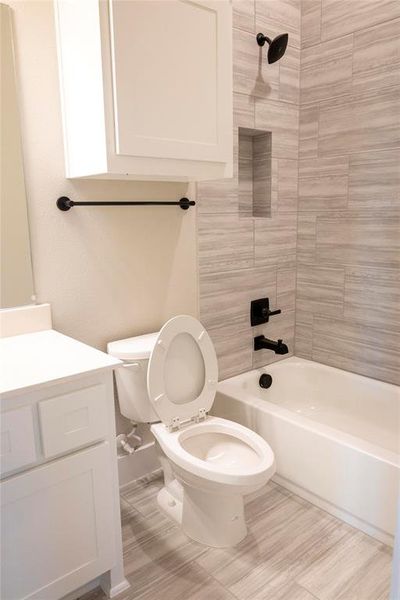 Full bathroom with vanity, tile patterned flooring, tiled shower / bath combo, and toilet