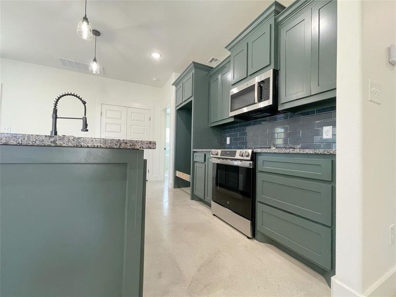 Kitchen featuring pendant lighting, decorative backsplash, appliances with stainless steel finishes, and green cabinets