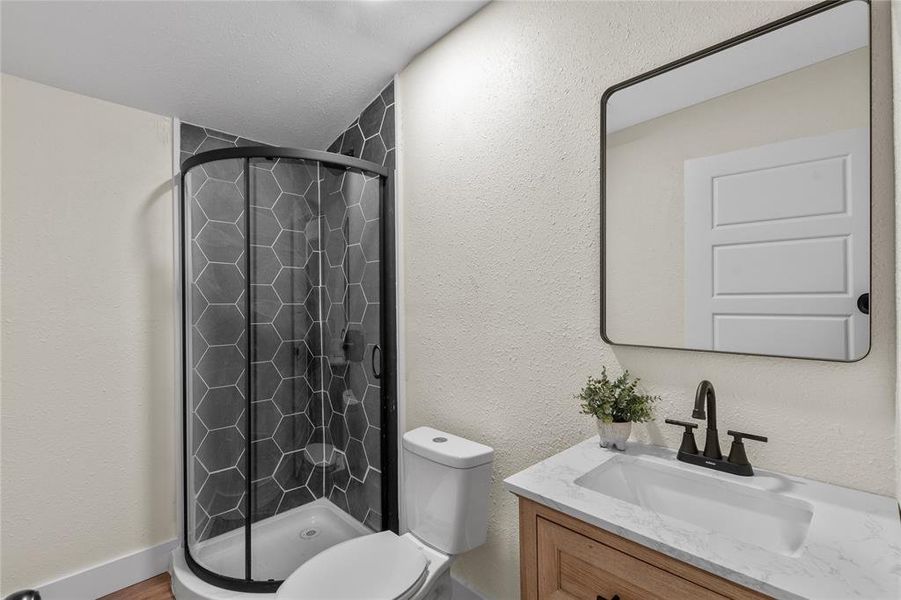 Bathroom with vanity, a shower with shower door, a textured ceiling, and toilet