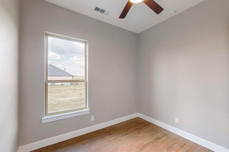 Empty room featuring ceiling fan, plenty of natural light, and light hardwood / wood-style floors