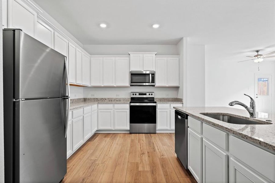 Chef ready kitchen with plenty of storage, granite countertops, designer white cabinetry, luxury vinyl plank flooring and a suite of energy-efficient Whirlpool appliances - including refrigerator with ice maker.