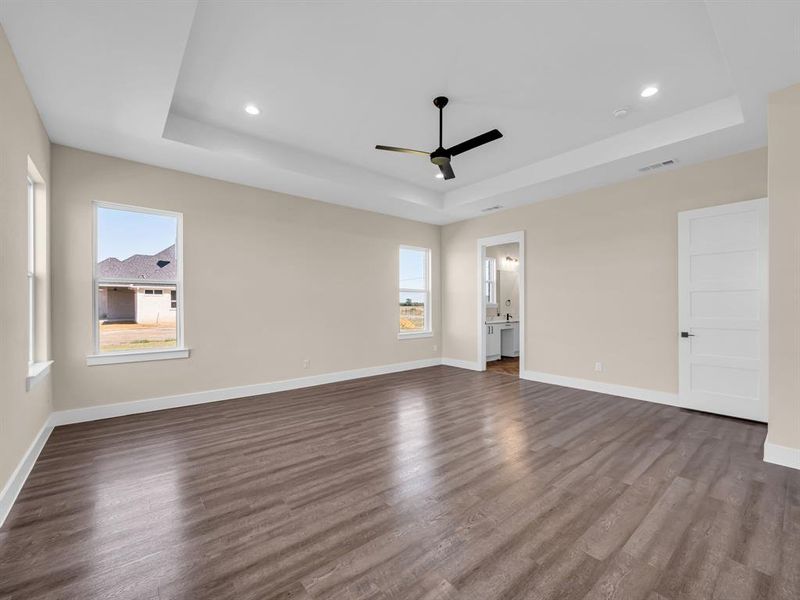 Empty room featuring ceiling fan, a tray ceiling, and hardwood / wood-style floors