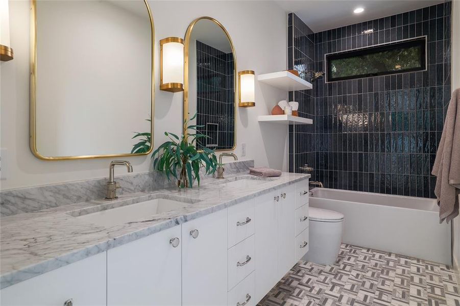 The second floor shared bath juxtaposes a stunning blue wall tile with a beautiful marble mosaic floor, soft white cabinetry, and a natural carrara countertop.