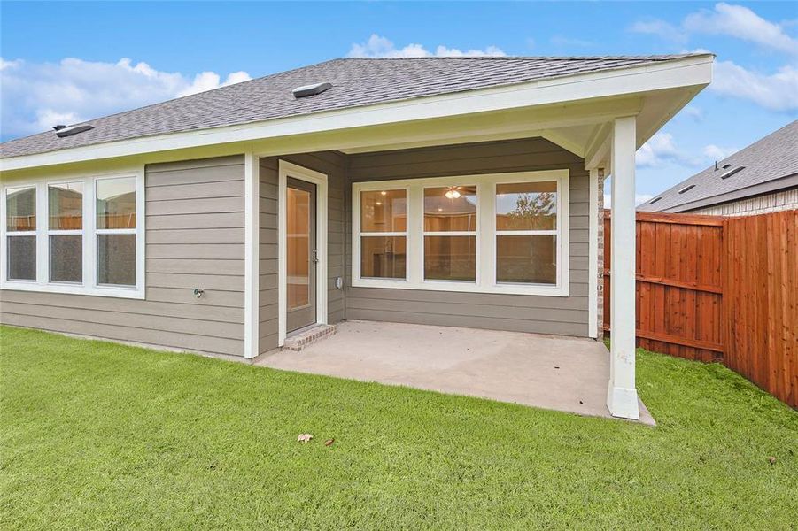 Rear view of house with a lawn and a patio area