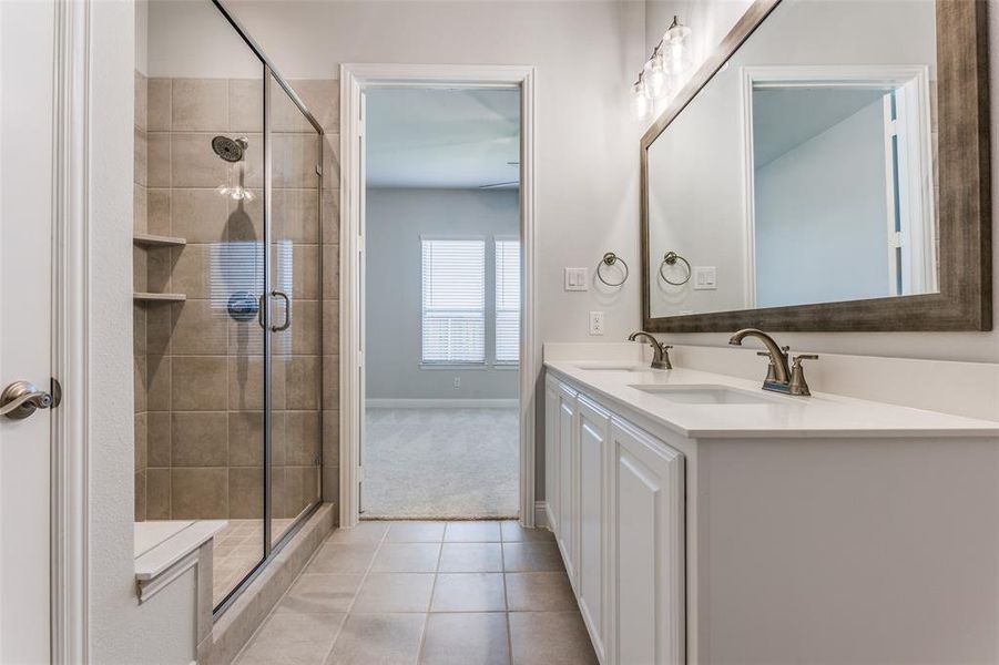 Bathroom featuring tile floors, a shower with shower door, and double vanity