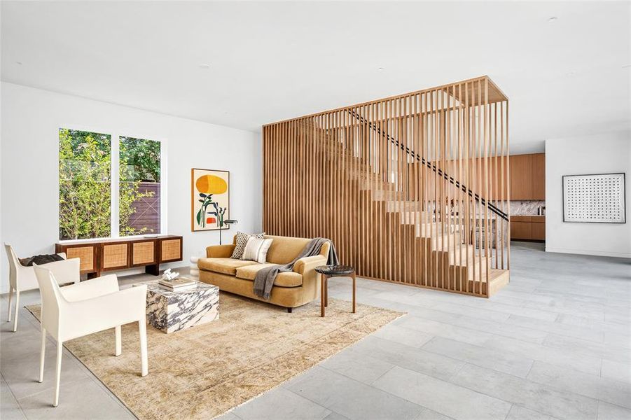 The expansive living area is highlighted by a stunning custom-built slatted walnut wall feature that elegantly encloses the staircase, creating a striking focal point. The open space is filled with natural light and seamlessly combines modern design with warmth, making it an ideal setting for relaxation and entertaining.