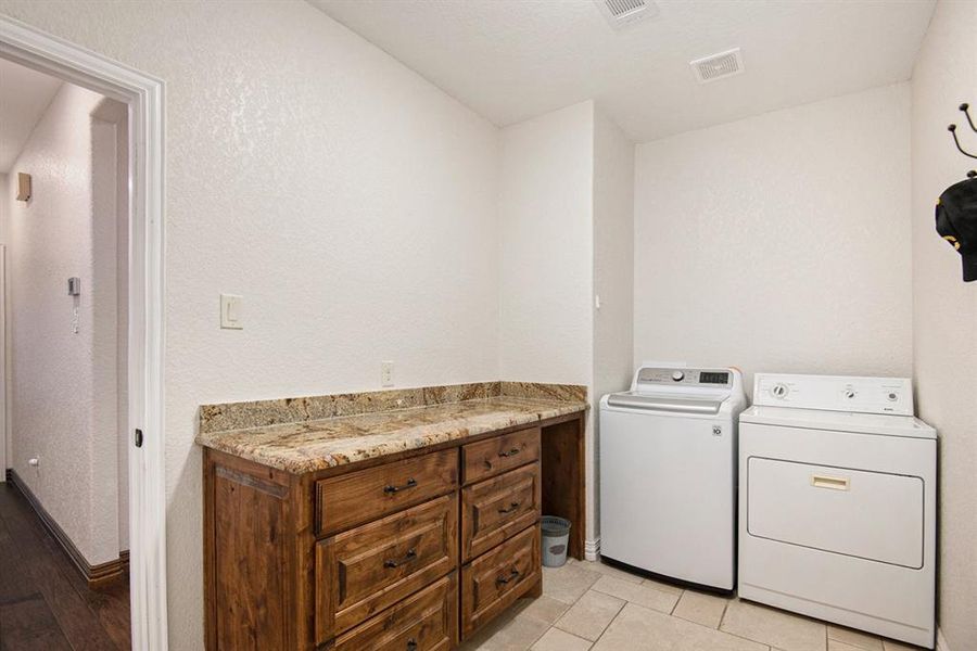 Clothes washing area with light tile patterned floors and washer and clothes dryer