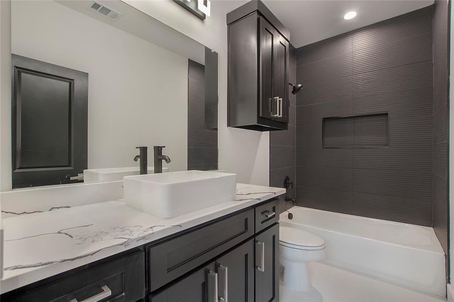 Full bathroom featuring tiled shower / bath combo, toilet, and vanity