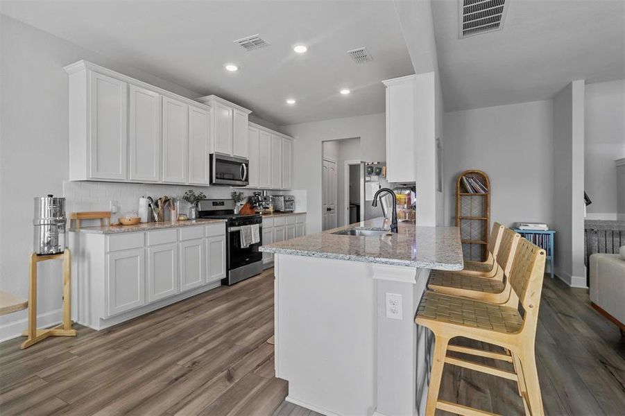 Kitchen with sink, white cabinets, stainless steel appliances, and dark hardwood / wood-style flooring