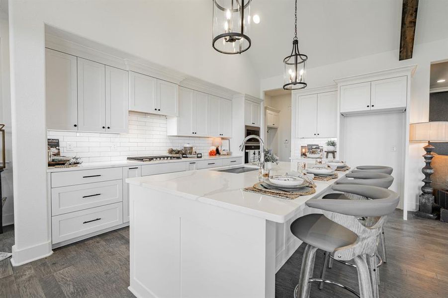 Kitchen featuring an island with sink, decorative light fixtures, dark hardwood / wood-style floors, and white cabinetry