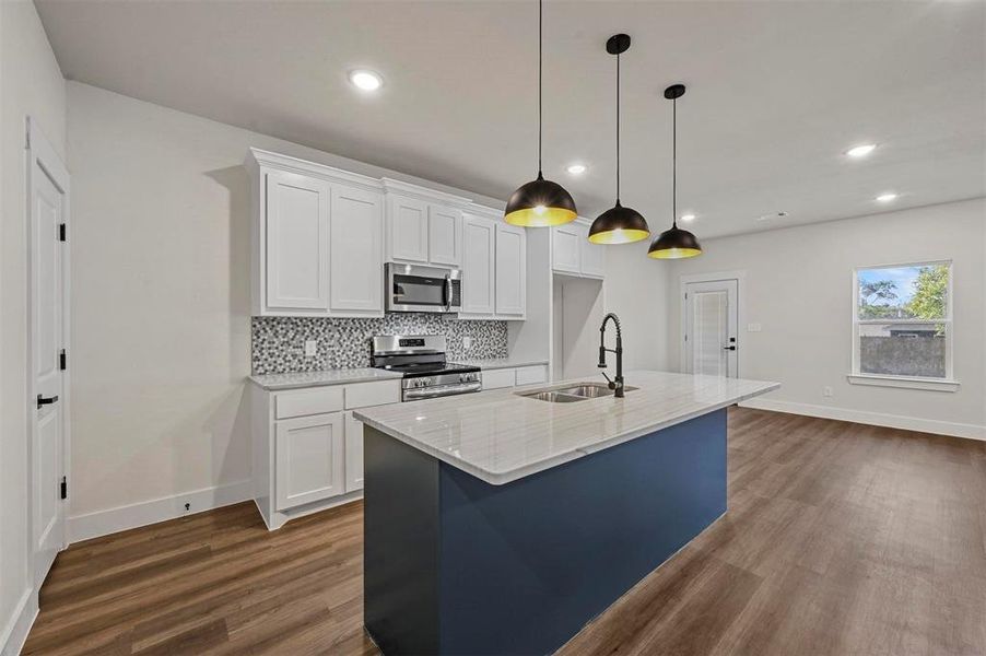 Kitchen with stainless steel appliances, white cabinets, hardwood / wood-style flooring, and sink