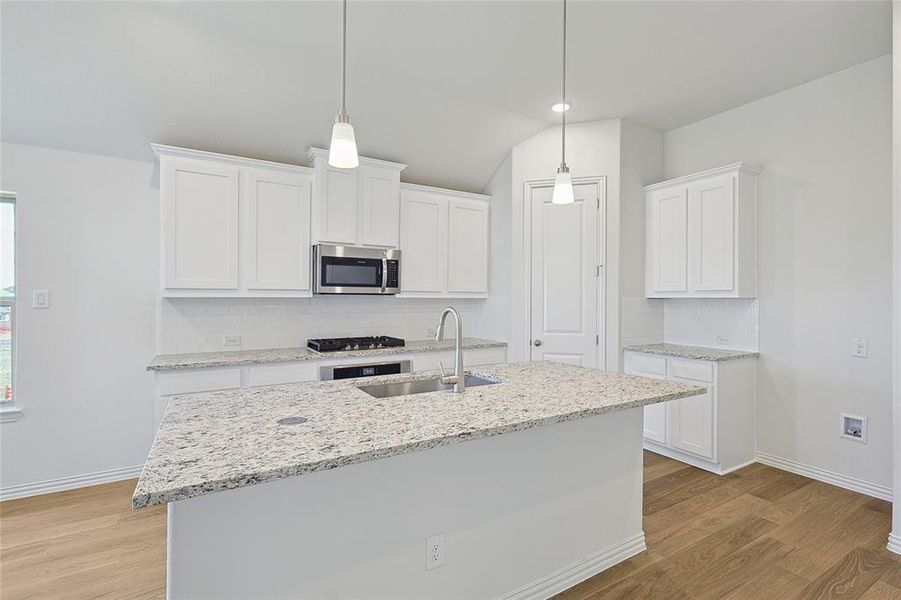 Kitchen featuring stainless steel appliances, white cabinetry, and light hardwood / wood-style floors