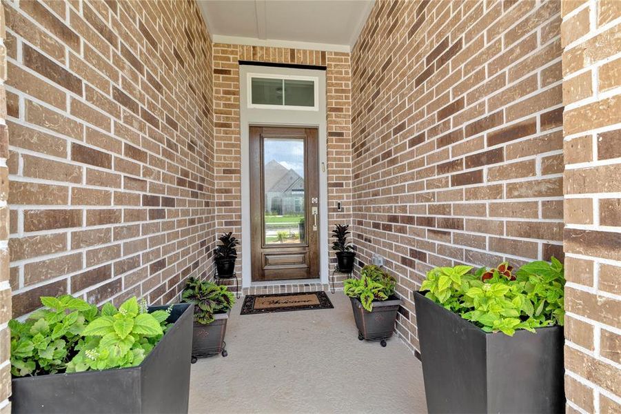 Inviting Walkway - Front walkway to the elegant stained door entrance, lined with full brick and covered, providing a warm welcome and a glimpse of the stunning interior beyond.