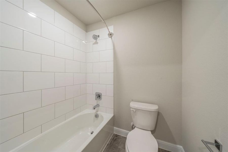 Bathroom featuring hardwood / wood-style floors, tiled shower / bath, and toilet