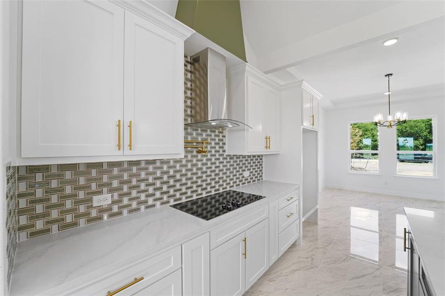 Kitchen featuring wall chimney range hood, light stone counters, black electric cooktop, tasteful backsplash, and light tile floors