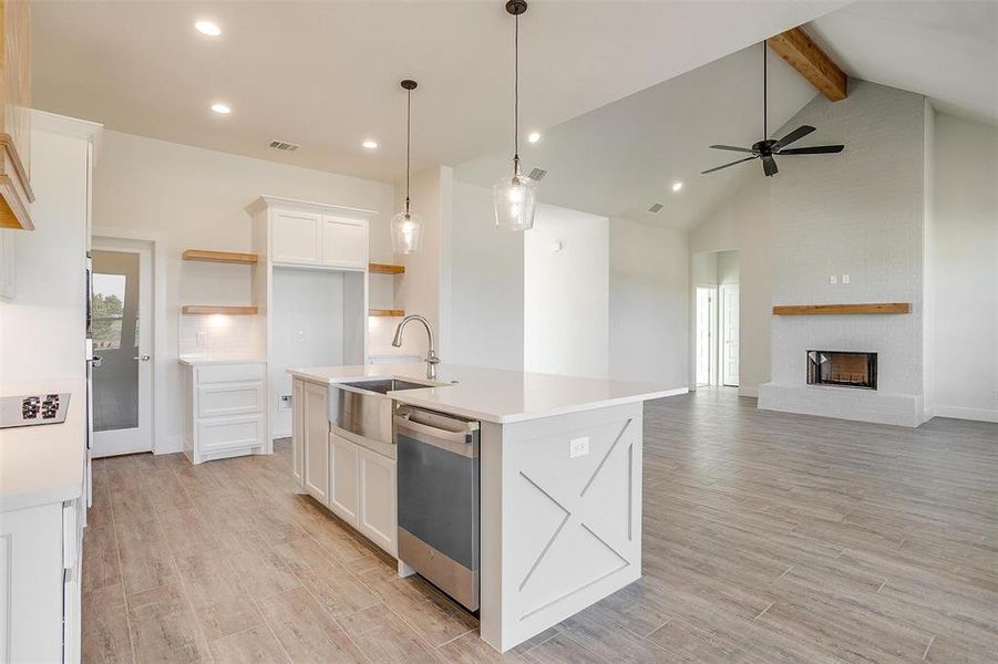 Kitchen featuring white cabinets, a kitchen island with sink, dishwasher, light hardwood / wood-style floors, and sink