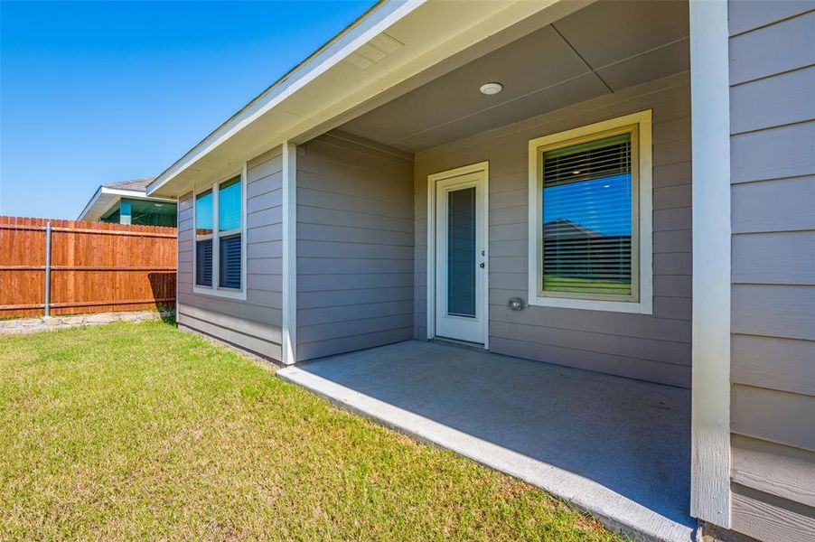 View of exterior entry with a yard and a patio area