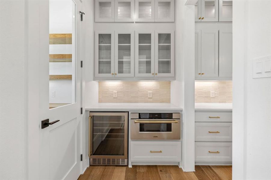 Bar featuring decorating, stainless steel oven, wine cooler, and light wood-type flooring