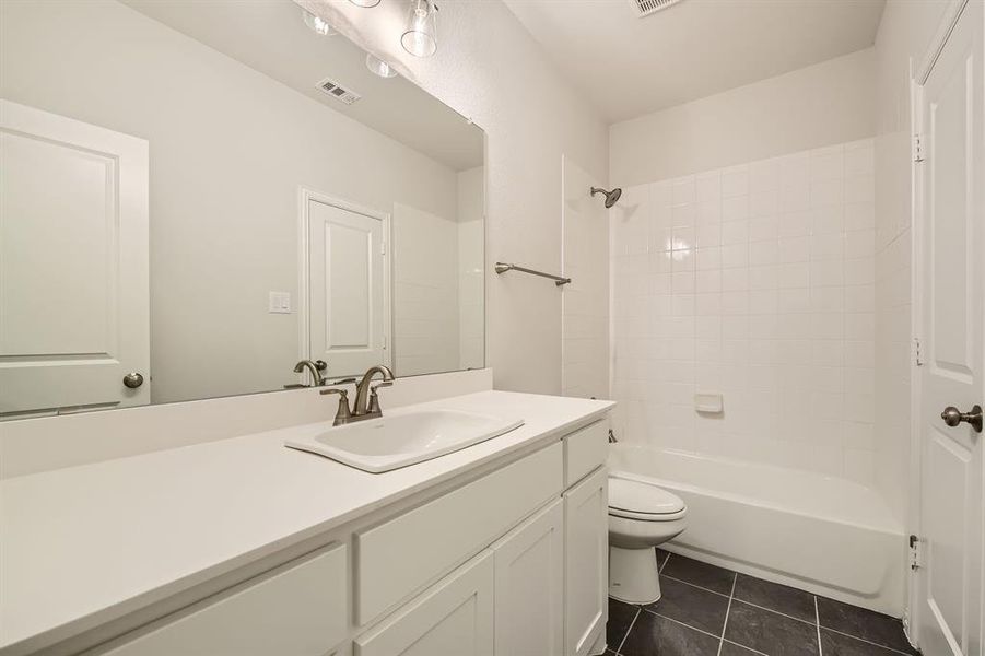 Full bathroom featuring toilet, tiled shower / bath combo, vanity, and tile patterned flooring