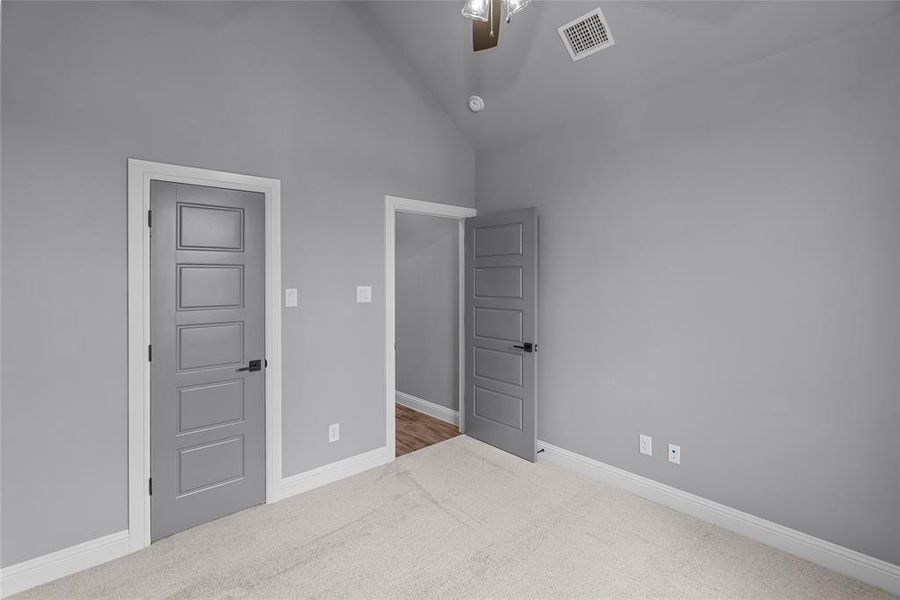 Unfurnished bedroom featuring ceiling fan, carpet flooring, and high vaulted ceiling