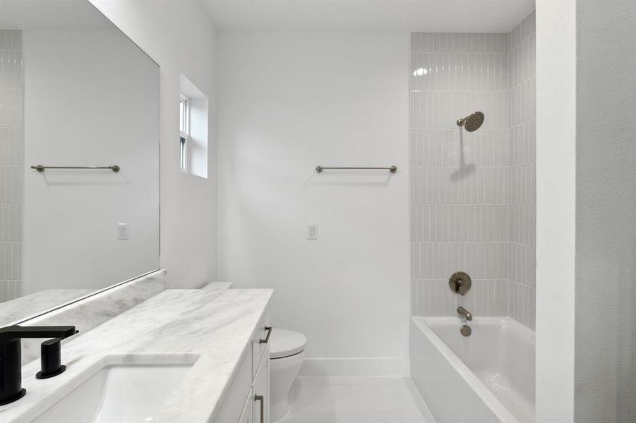 Full bathroom featuring tile patterned floors, tiled shower / bath, vanity, and toilet