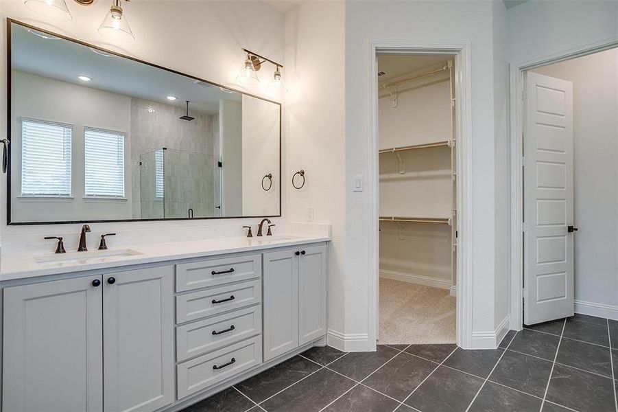 Bathroom featuring an enclosed shower, tile patterned flooring, and dual bowl vanity