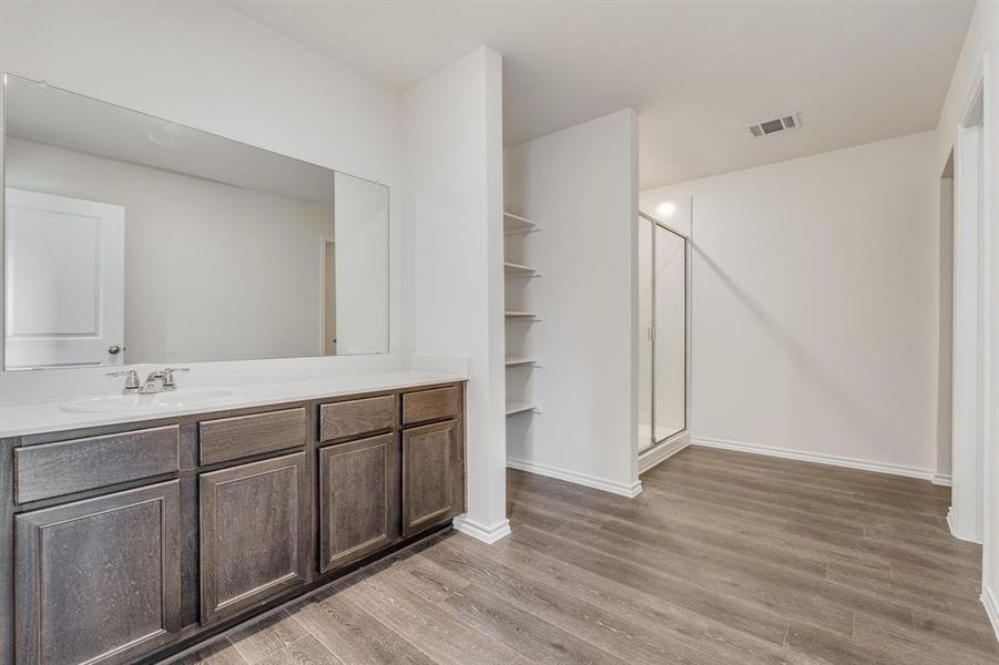 Bathroom featuring wood-type flooring, vanity, and a shower with door