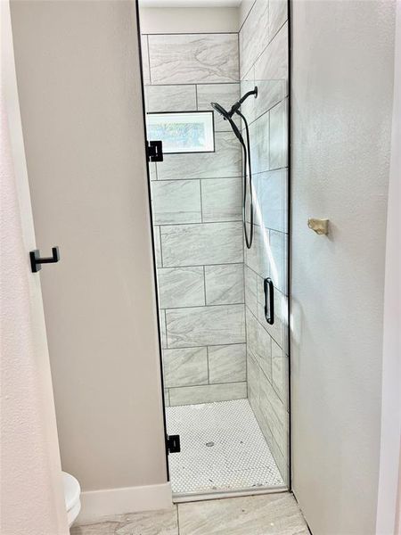 Bathroom featuring a shower with shower door and toilet