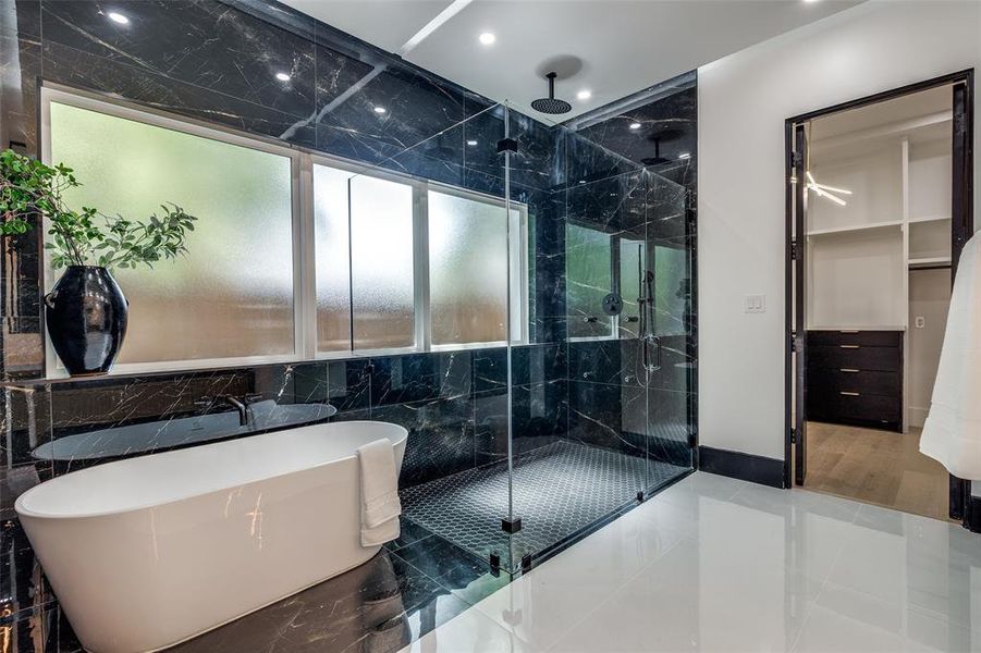 Bathroom with shower with separate bathtub, tile flooring, and tile walls