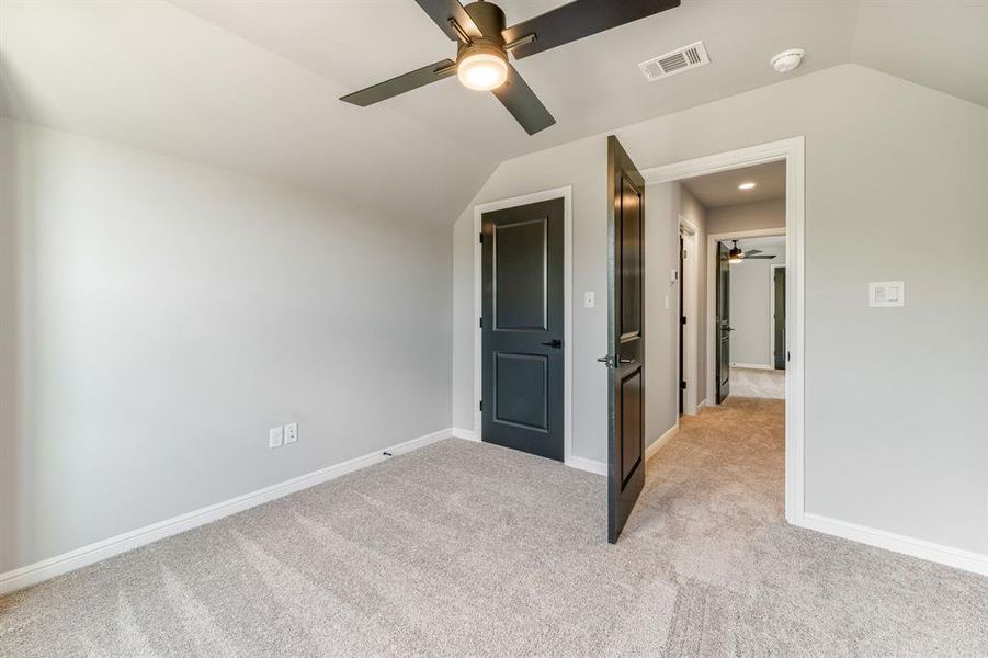 Unfurnished bedroom with light carpet, lofted ceiling, and ceiling fan