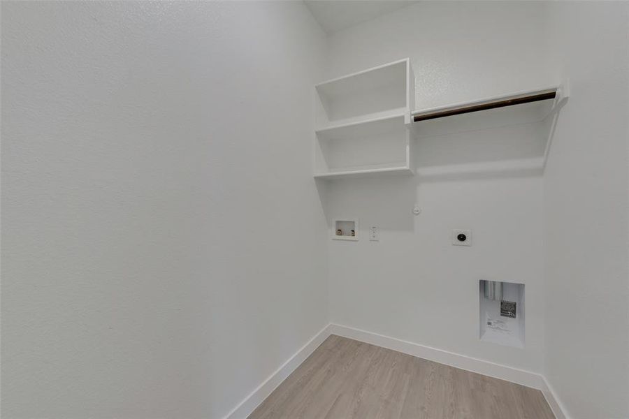 Laundry area with light wood-type flooring, hookup for a washing machine, hookup for an electric dryer, and gas dryer hookup