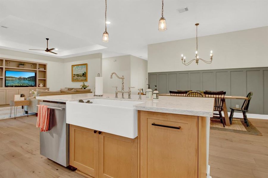 This expansive open-concept living space includes the modern kitchen with a large island, farmhouse sink, and elegant pendant lighting, seamlessly flowing into a dining area.