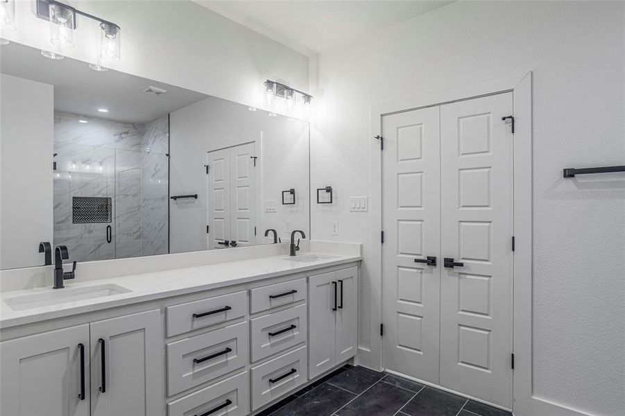 Bathroom with tile patterned flooring, double sink vanity, and a shower with door